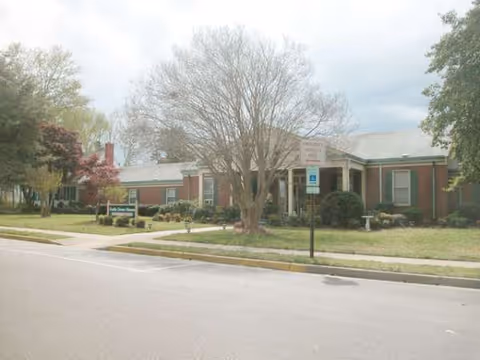 One-story brick senior living facility with a front entrance and trees.