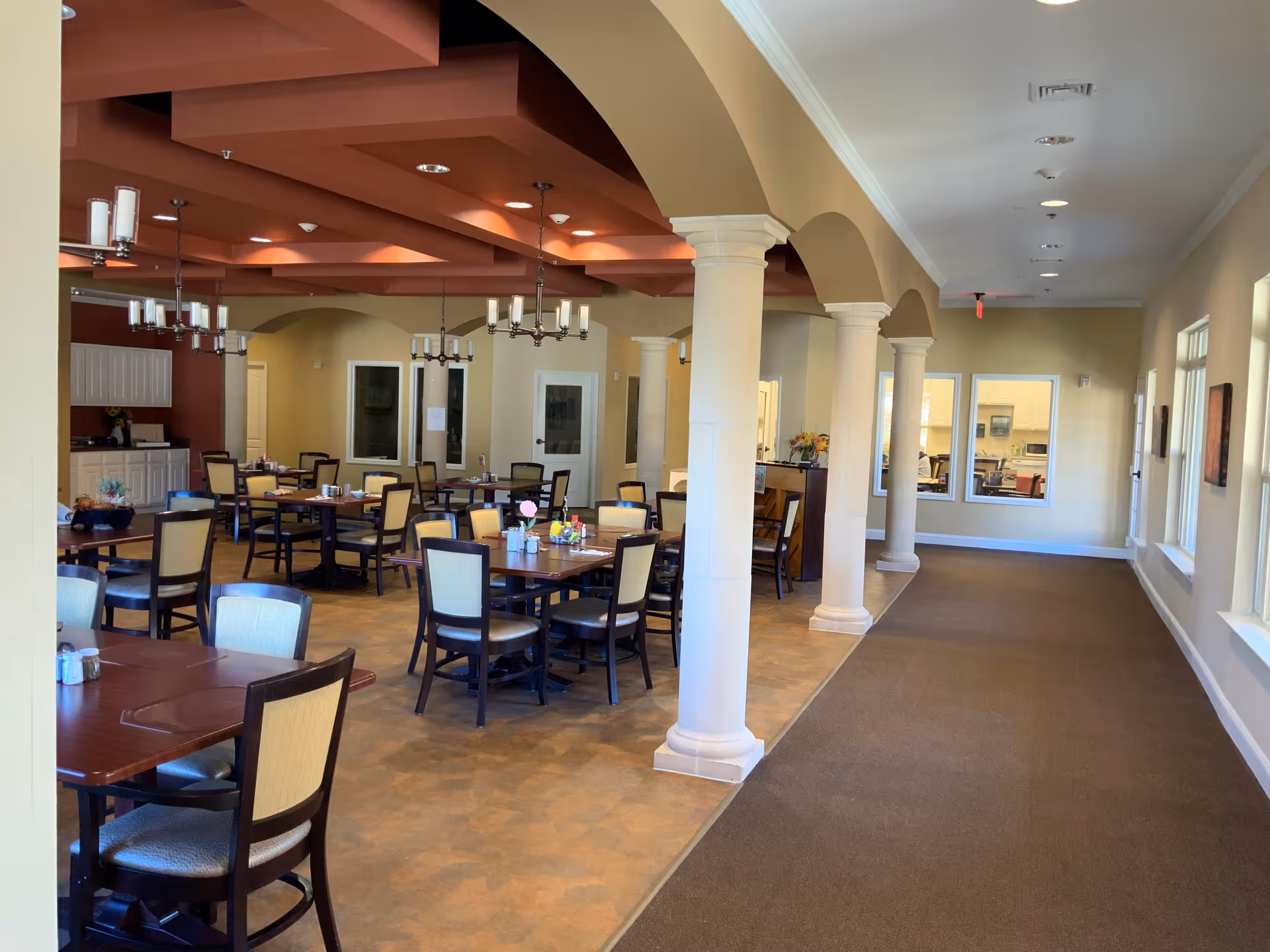 Spacious dining room with multiple tables and chairs, decorative columns, arches and chandeliers.