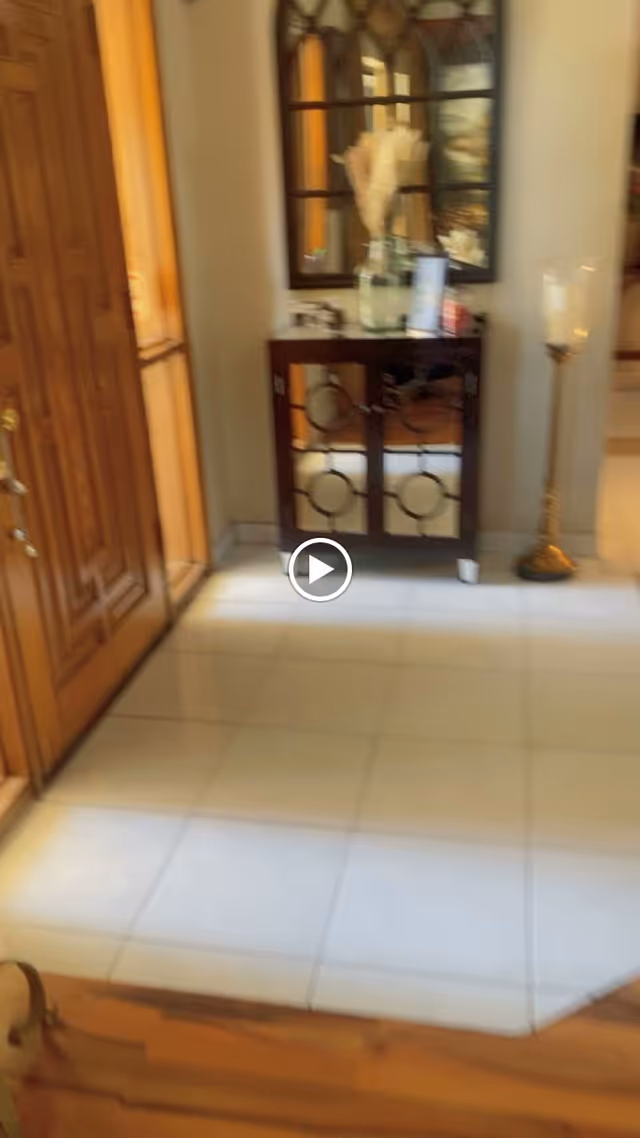 Entryway with a wooden front door, tiled floor, and a console table with a mirror and decorative items.