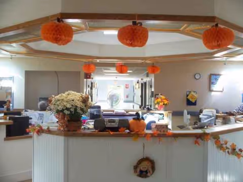 Interior lobby of a nursing home with front desk, decorations, and staff at work.