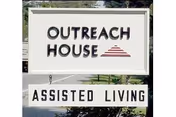 Outdoor sign that reads "OUTREACH HOUSE" with a small triangular logo and a lower panel reading "ASSISTED LIVING".