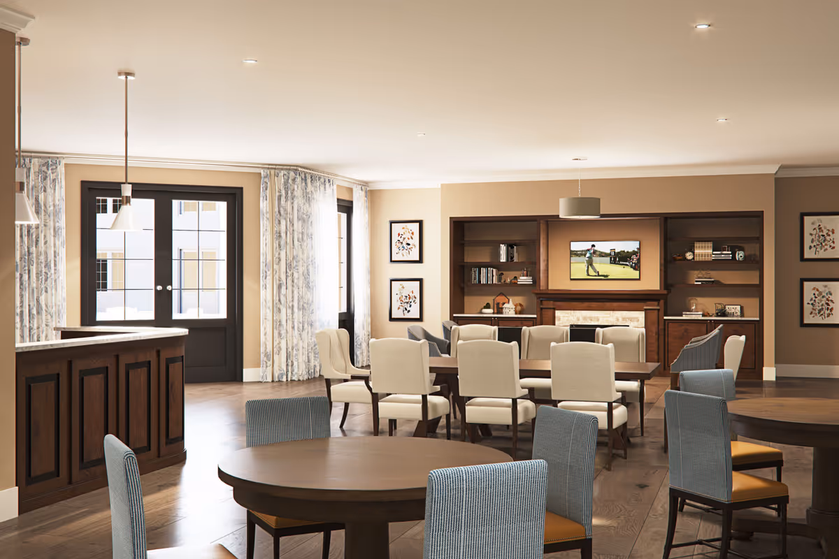 Bright communal dining and lounge area with multiple round and rectangular tables, upholstered chairs, a built-in media wall and large windows.