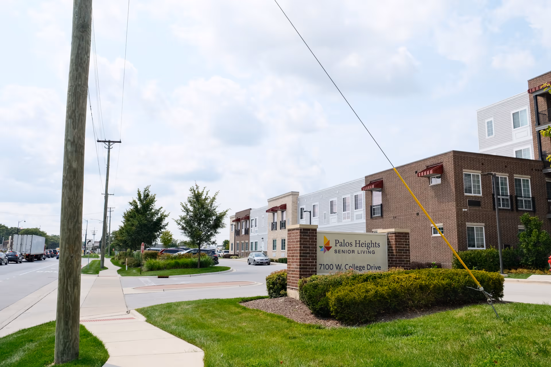 Exterior view of the Palos Heights Senior Living building with its entrance sign, landscaping, and adjacent street.