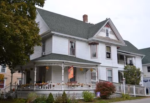 Front view of Burr Adult Residential Care Home, a two-story white house with a wraparound porch.