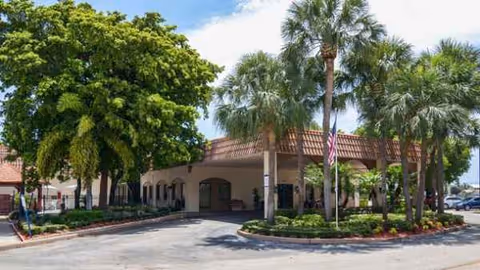 Exterior view of Manorcare Health Services Boca Raton entrance with palm trees.