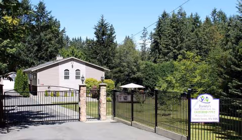 Gated entrance to Daniela's Adult Home Care building with a manicured lawn.