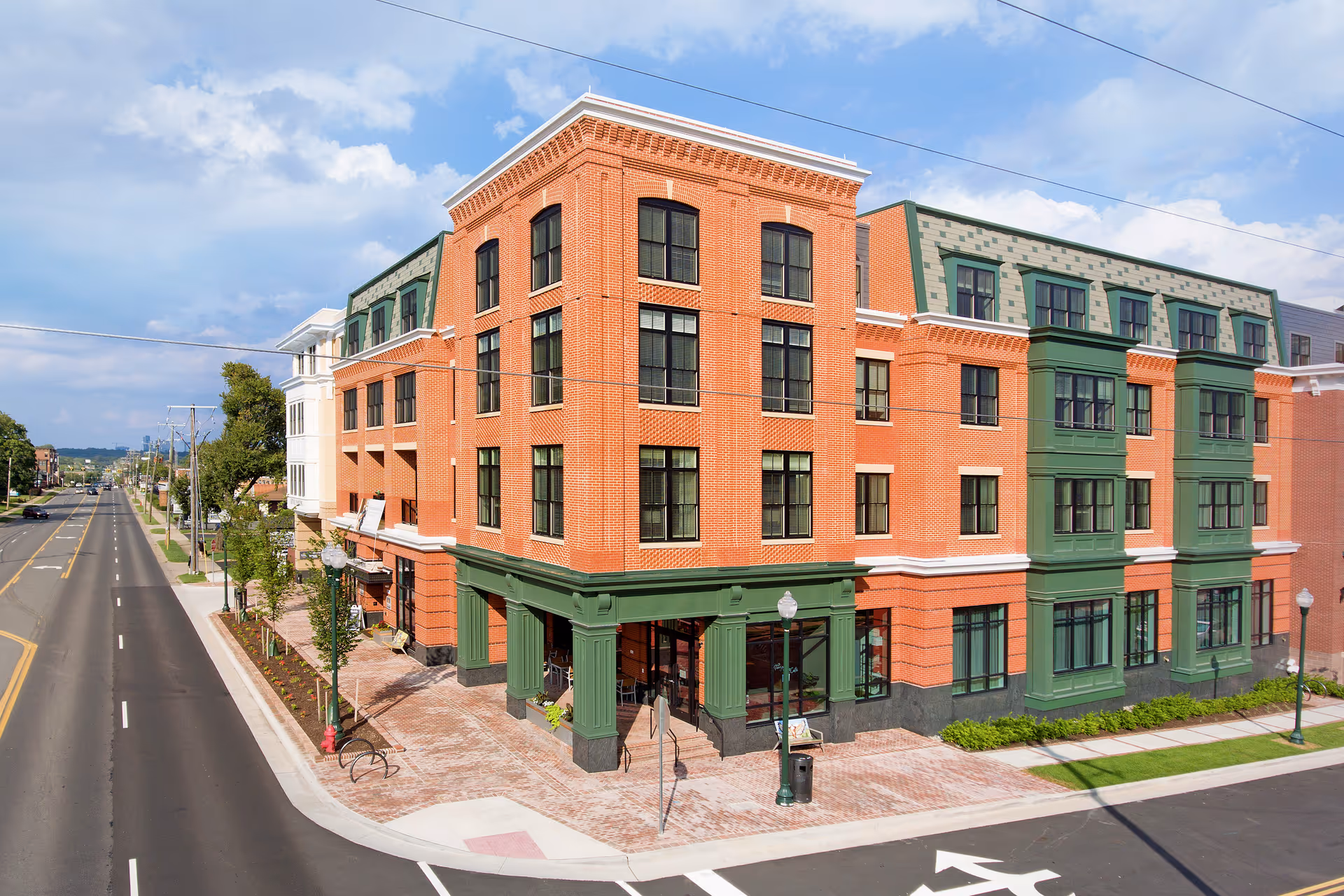 Sunrise of Vienna exterior: a three-story brick building with green trim on a sunny street corner.