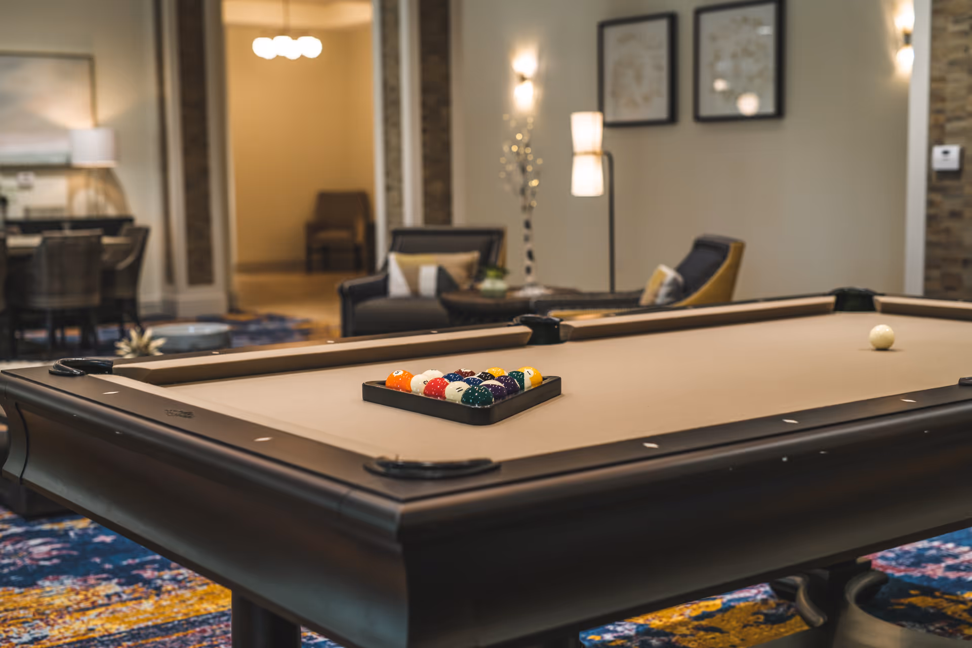 A pool table with racked billiard balls in a furnished lounge area.