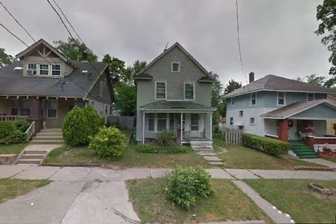 Row of suburban houses with front yards and sidewalks along a street.