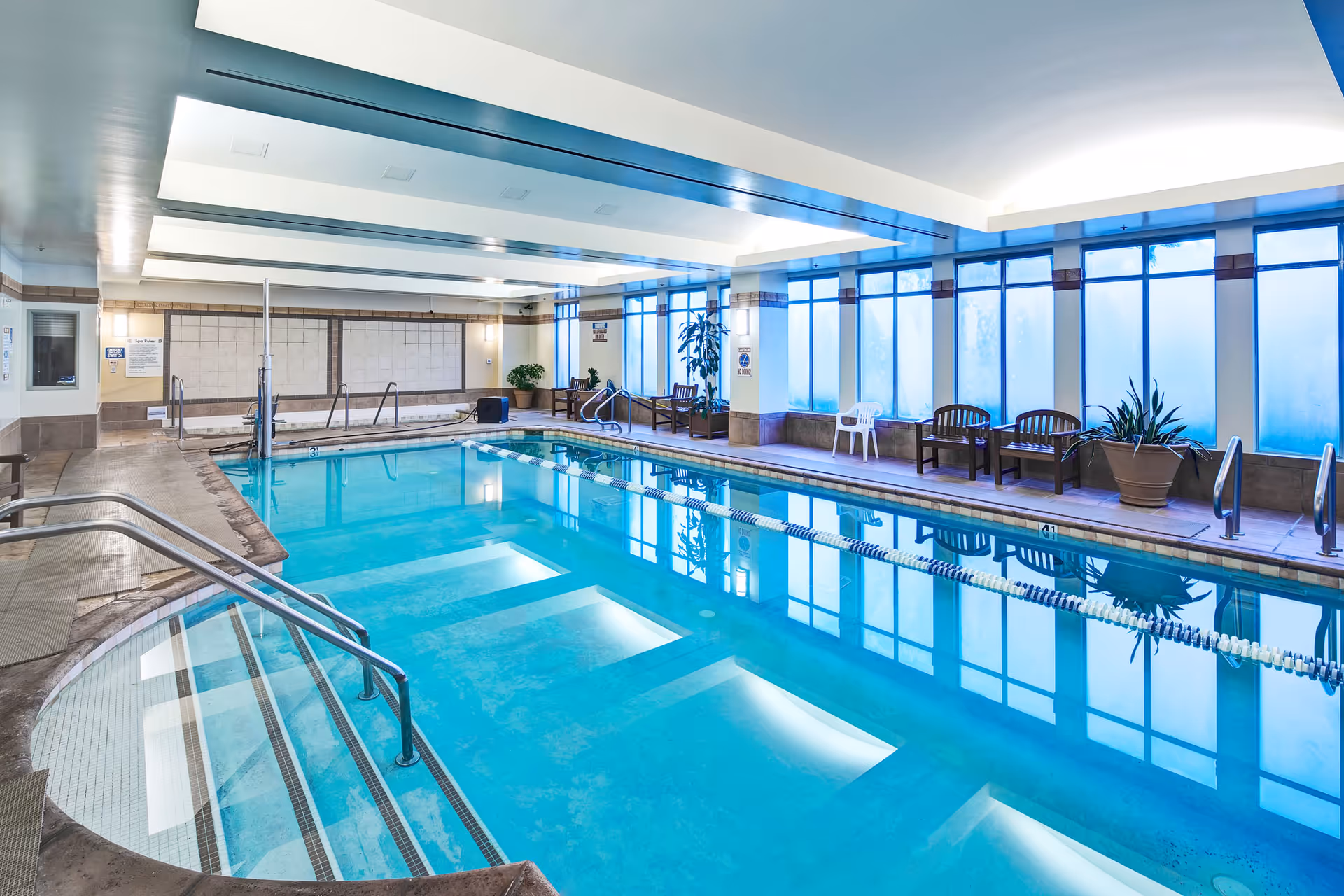 Indoor lap pool with seating along the windows and frosted glass panels.