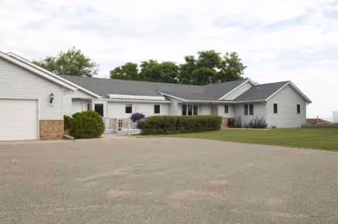 Single-story Valentines Assisted Living exterior with a parking lot and trimmed hedges.