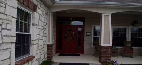 Front entrance of Brookdale Goodlettsville with red door, wreath, brick and siding exterior.