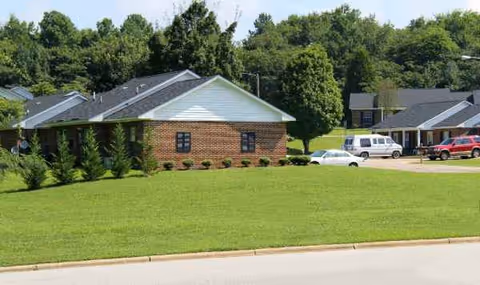 Exterior view of Wake Assisted Living Memory Care facility with brick building, lawn, and parked cars.