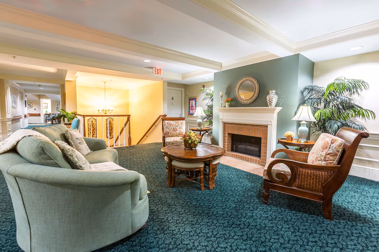 Cozy senior living lounge with sofas, armchairs, a coffee table, and a fireplace.