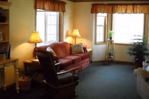 Cozy living room in a senior community with a red sofa, rocking chair, and lamps.
