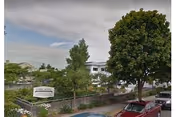 Outdoor view of Avamere Rehabilitation at Park West, with a sign, trees, and parked cars.