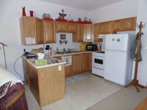Kitchen area with wooden cabinets, white appliances, and a small island.