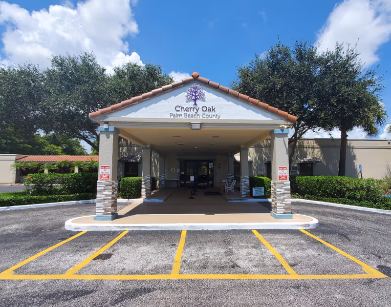 Front entrance of Cherry Oak Palm Beach County senior living facility with parking and trees.
