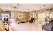Bright, spacious common lounge with sofas, armchairs, a television, and a reception desk.