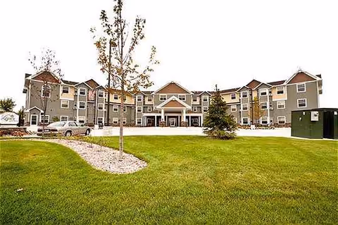 Exterior view of a multi-wing senior living building with green lawn and driveway.