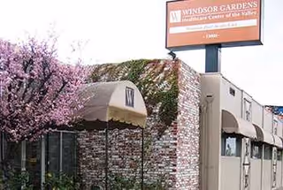 Exterior view of a brick senior living building with a canopy and pink flowering tree.
