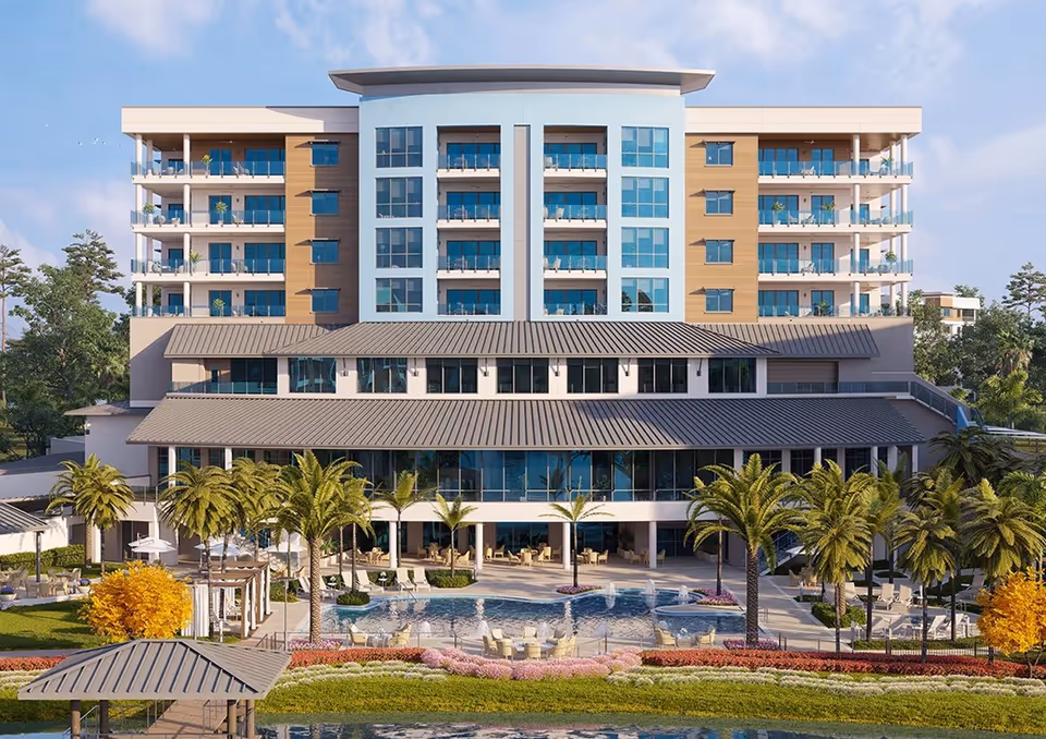 A modern multi-story building with balconies, palm trees and a swimming pool in front.