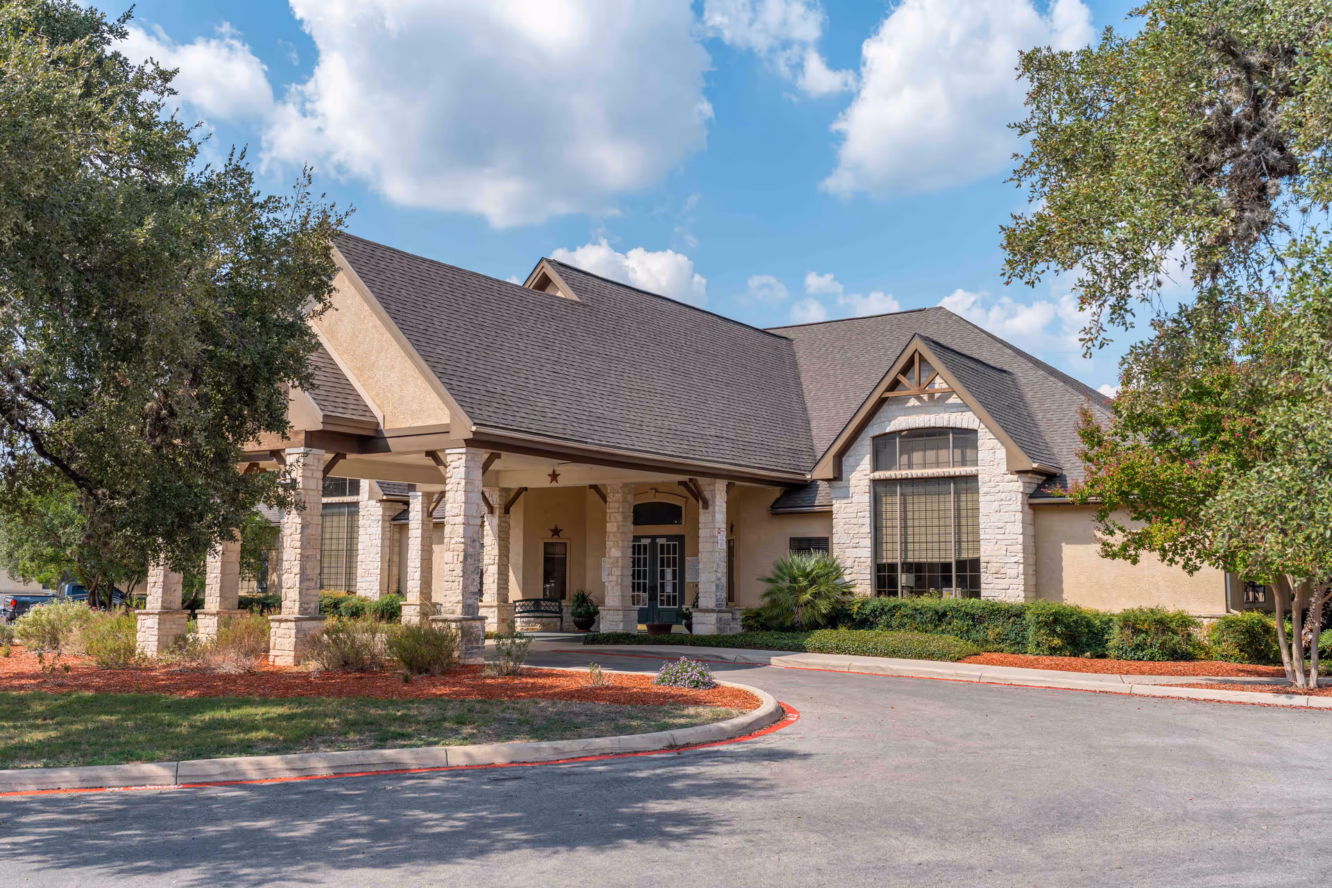 Exterior view of a senior living facility with a covered entrance and stone pillars.