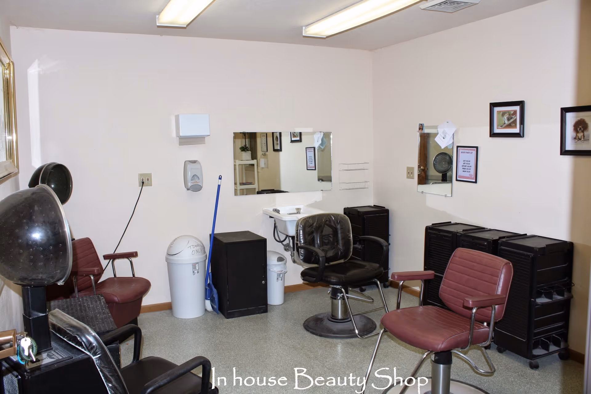 Interior view of an in-house beauty shop with salon chairs, hair dryers, mirrors, and hair styling equipment against light-colored walls.