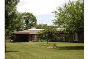 Front exterior of Benedictine Living Community-LaMoure, with lawn and trees.