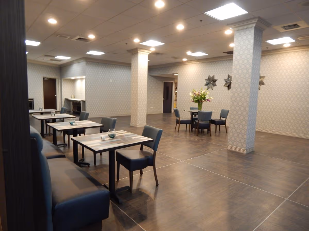 Spacious dining room with tables, chairs, booth seating, decorative columns, and a central flower arrangement.