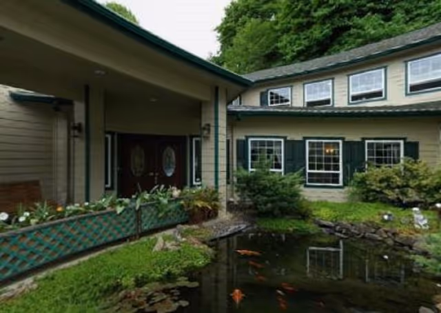 Senior living facility entrance with a pond and greenery in front.