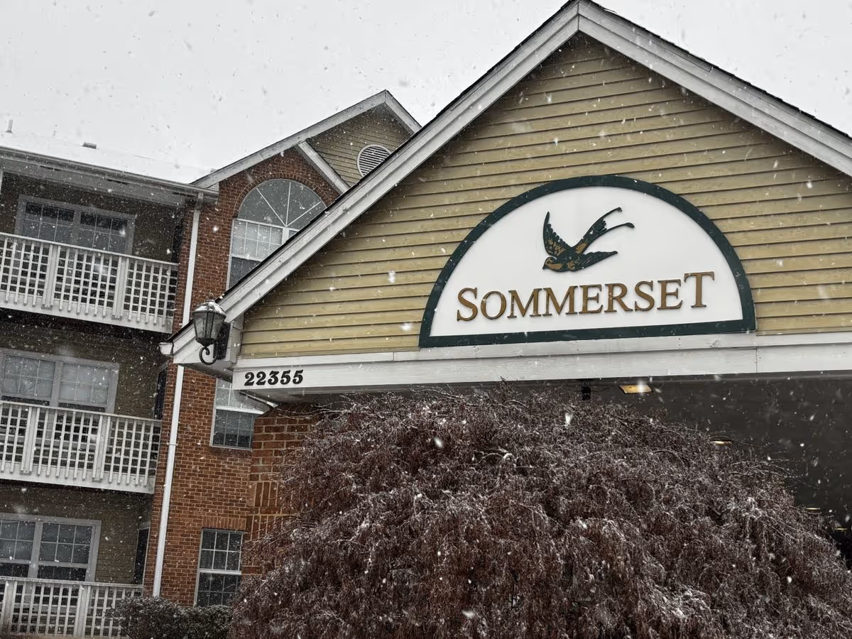 Entrance of the Sommerset Retirement Community building with a large sign and falling snow.