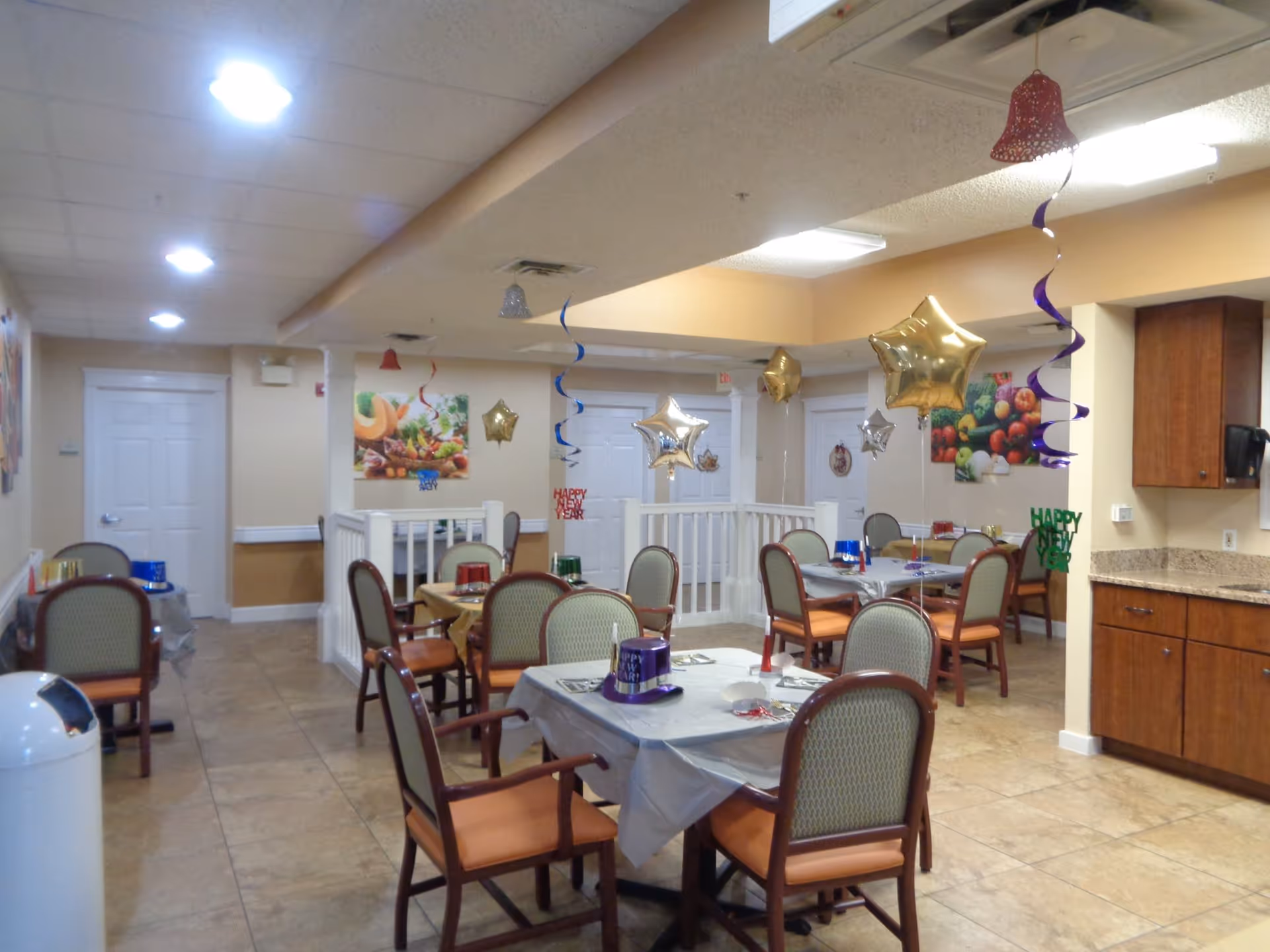 Dining room with multiple tables and chairs decorated with star-shaped balloons and streamers for a celebration.
