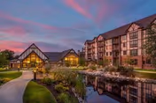 Evening exterior view of Beacon Hill at Eastgate featuring a lit entrance, pond, and landscaped path.