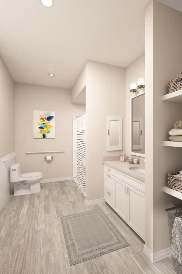 A clean and spacious bathroom with light-colored walls and wood-patterned flooring. The room features a toilet, a shower with a striped curtain, a vanity with a sink, mirror, and lighting fixtures above. There are open shelves on the right side holding towels and baskets, and a colorful abstract painting hangs on the wall above the toilet.