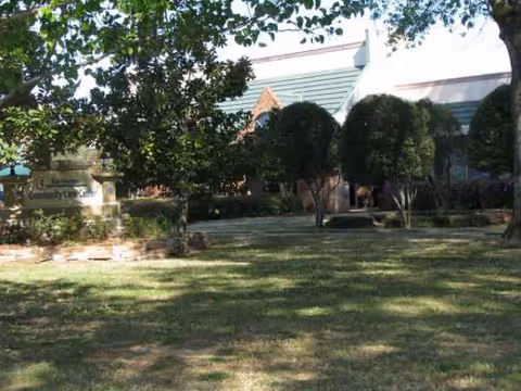 Exterior view of Community Care Center with trees, lawn, and a covered entrance.