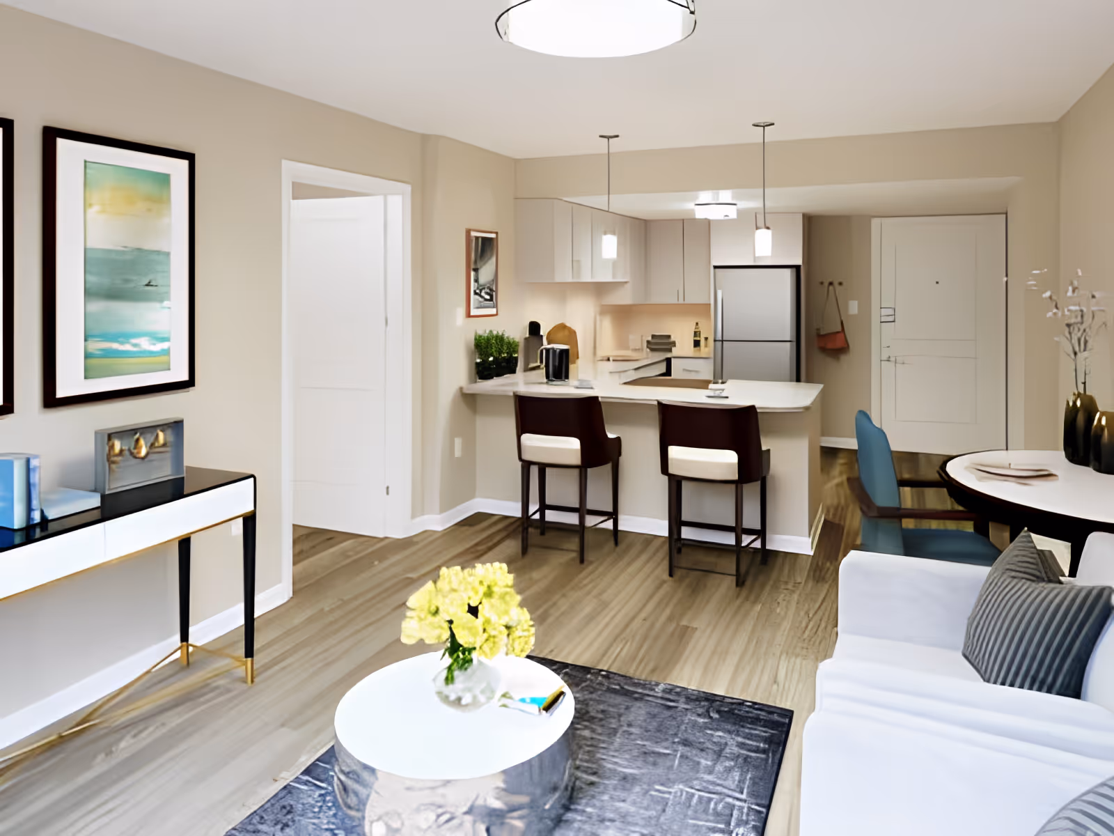 Open-plan living area with a sofa and coffee table facing a kitchen island with two bar stools in a modern apartment.