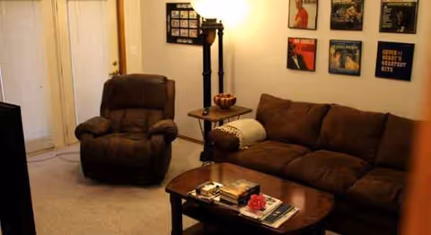 Cozy brown living room with sofa, armchair, coffee table, and wall art.
