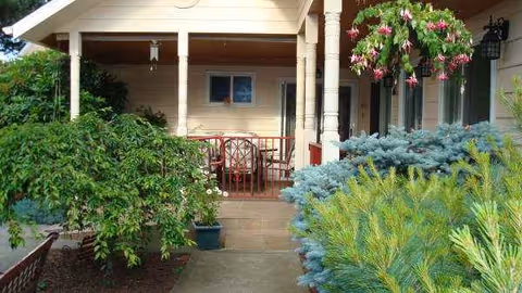 Front porch of Lia's Elder Care Home with plants, hanging basket, and seating.