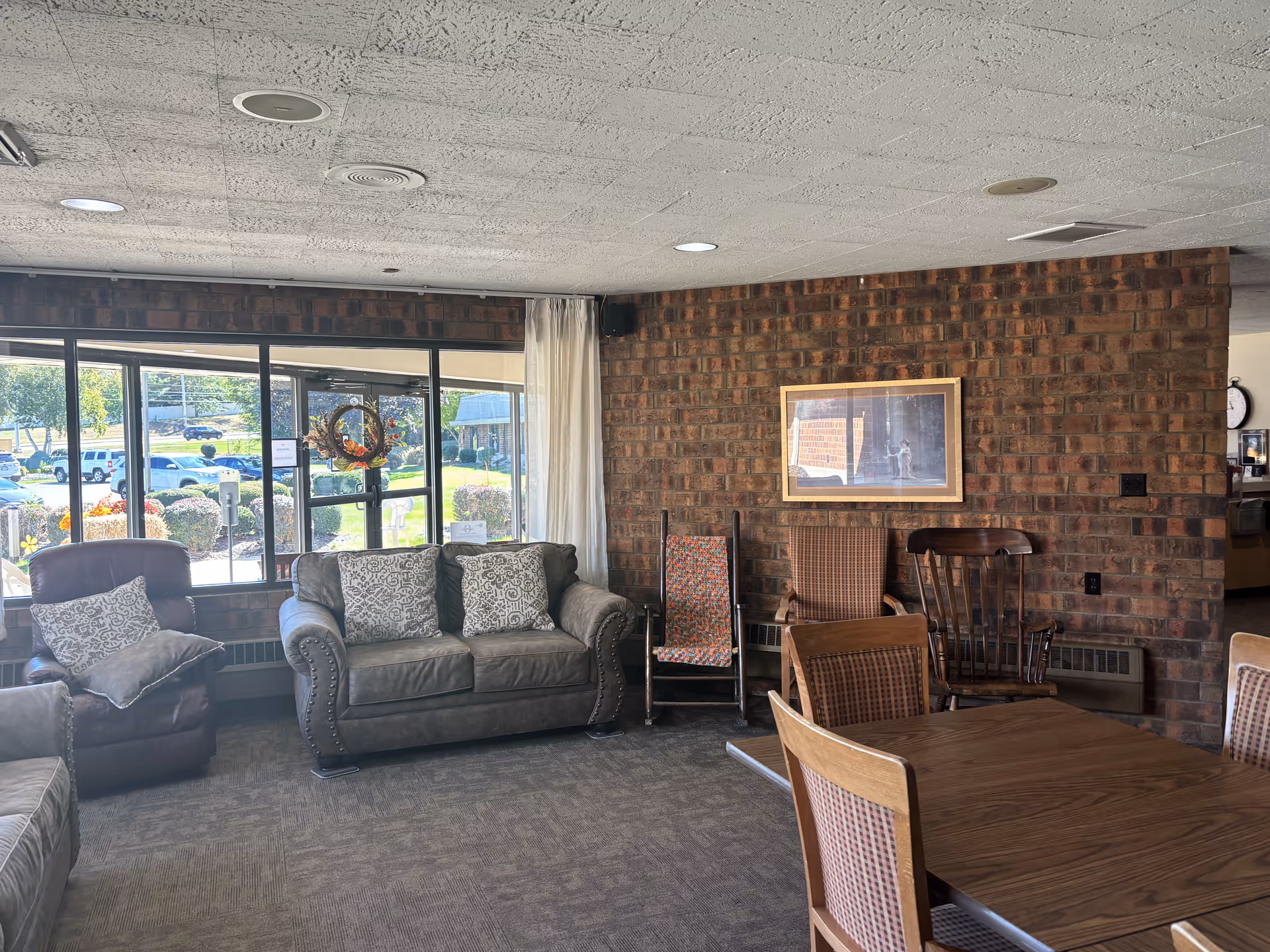 A cozy living area with couches, chairs, and large windows overlooking an outdoor space.