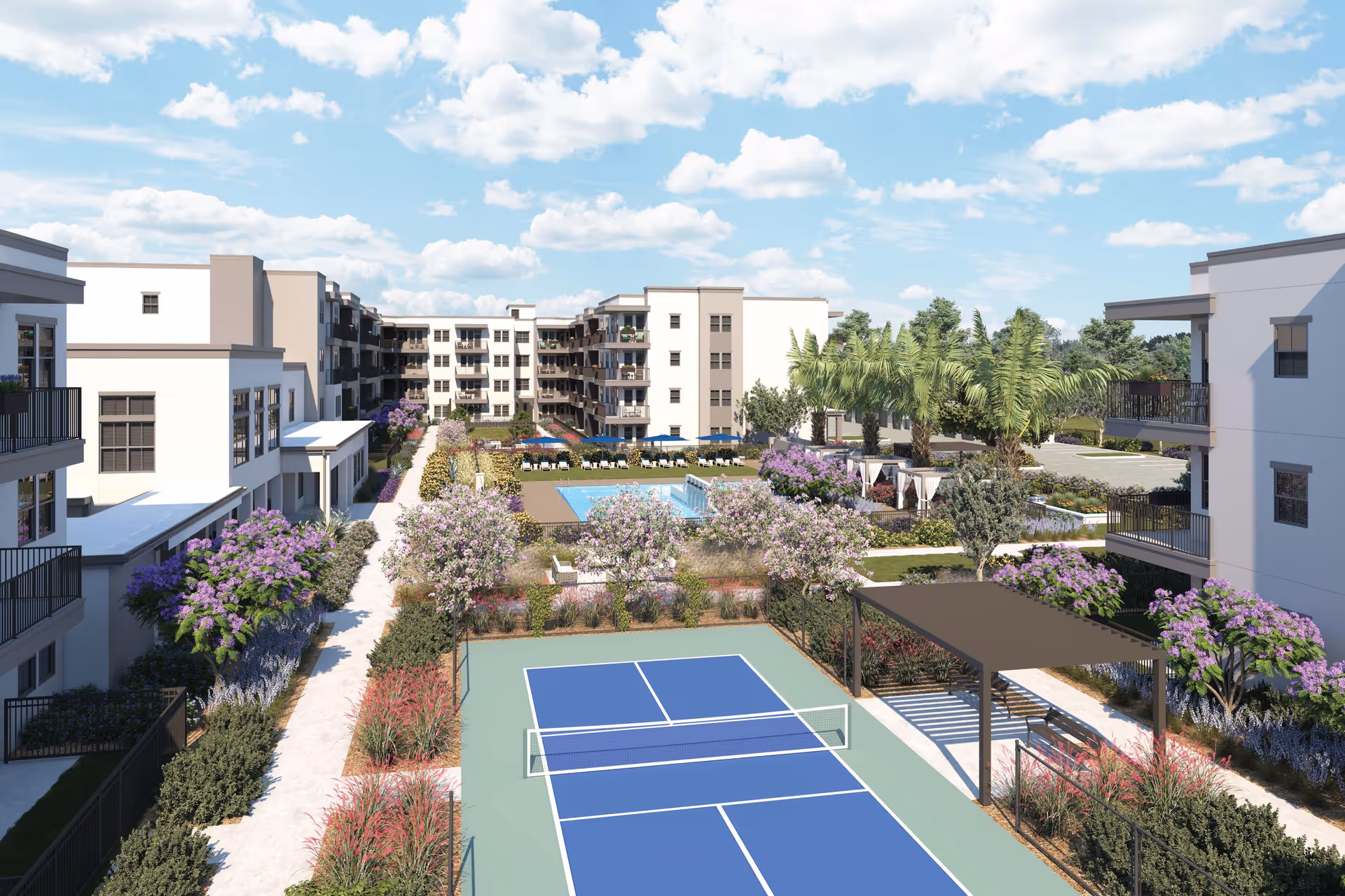 Outdoor view of a senior living facility named Mera Goodyear featuring a tennis court in the foreground, landscaped gardens with flowering trees and shrubs, a swimming pool with lounge chairs and umbrellas, and multi-story residential buildings surrounding the area under a partly cloudy sky.