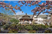 Exterior view of Emerald Heights featuring a central gazebo, blooming trees, and landscaped courtyard.