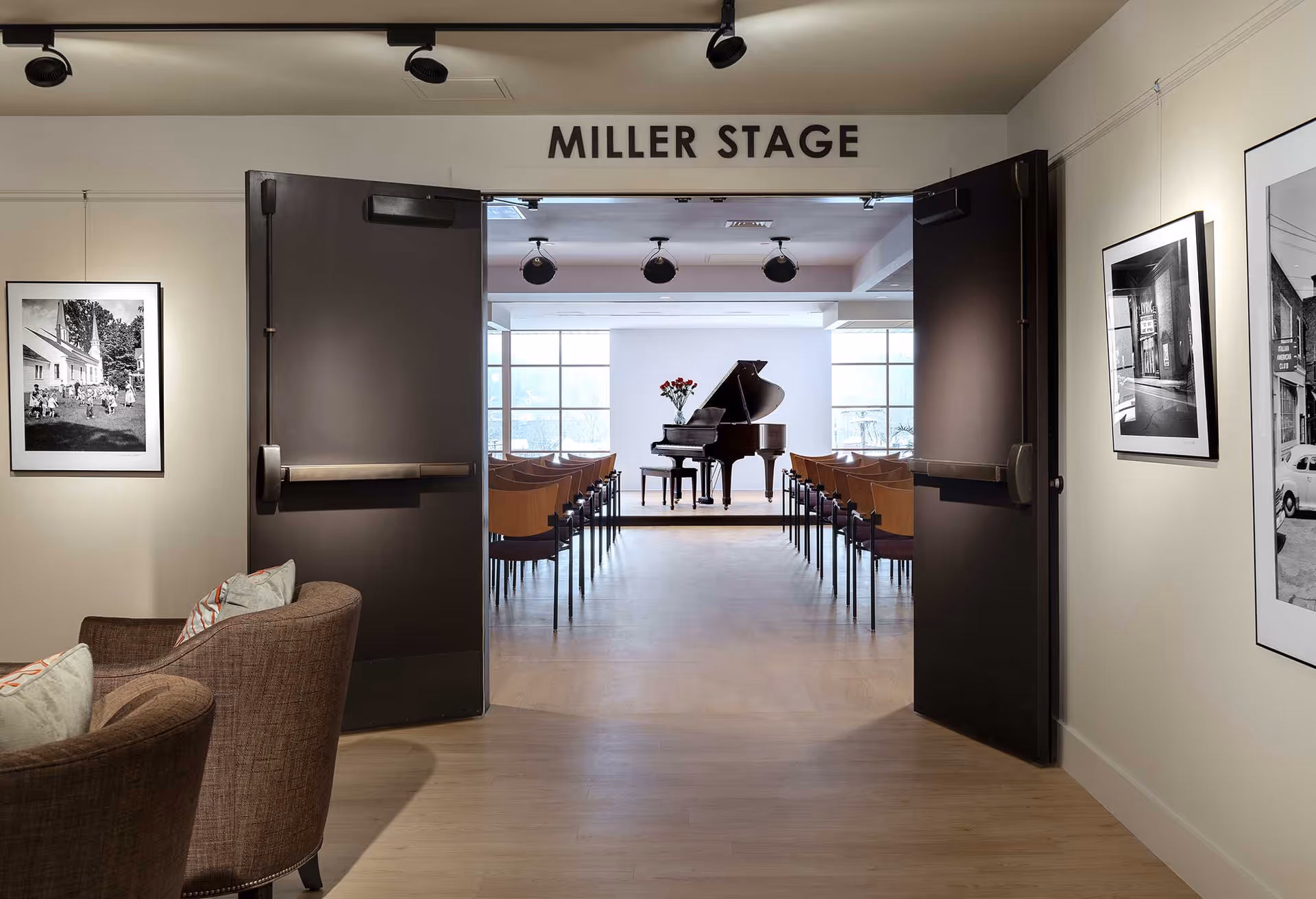 Open double doors labeled "MILLER STAGE" reveal an interior performance room with a grand piano and rows of chairs, framed photos on the walls, and lounge seating in the foreground.