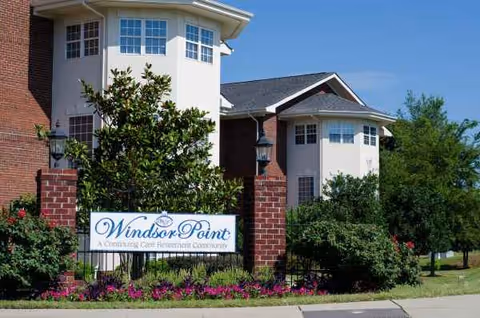 Front exterior of Windsor Point senior living facility with sign and landscaping.