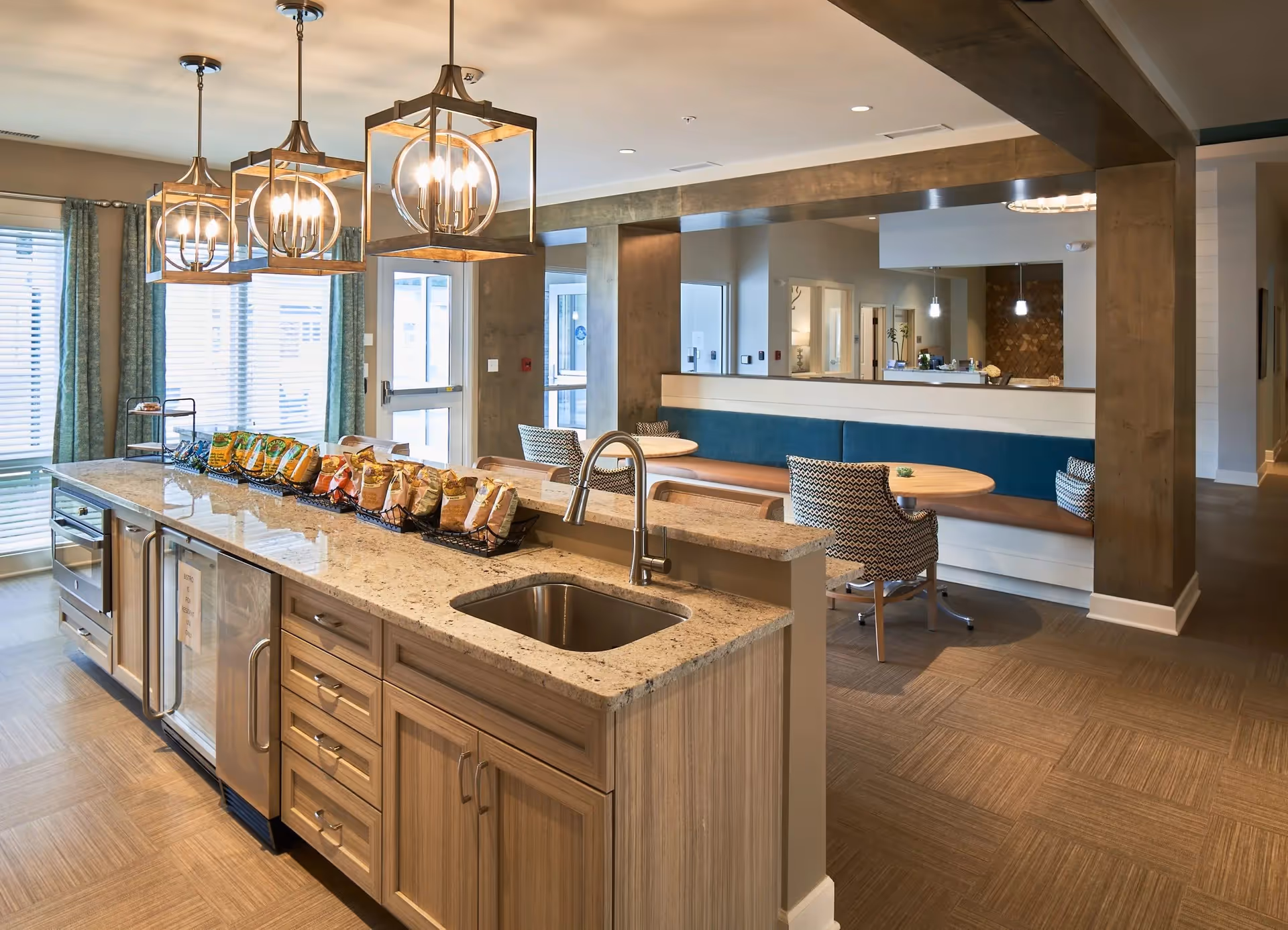 Open communal kitchen and dining area featuring a large island with sink and snacks, pendant lights, and banquette seating.