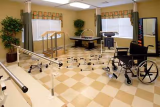 Rehabilitation room with parallel bars, wheelchair, treadmill, and balance equipment.
