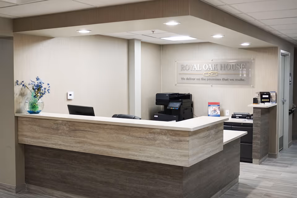Reception desk and office area with a sign reading 'ROYAL OAK HOUSE' on the back wall.