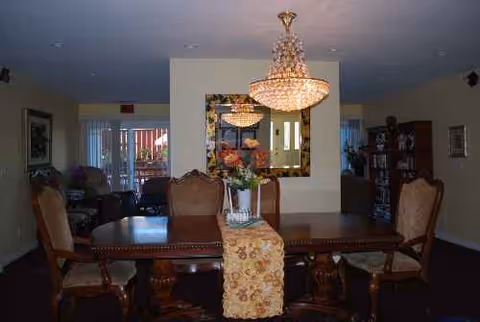 Millbrae Board and Care dining room with chandelier, floral centerpiece, and wooden chairs.