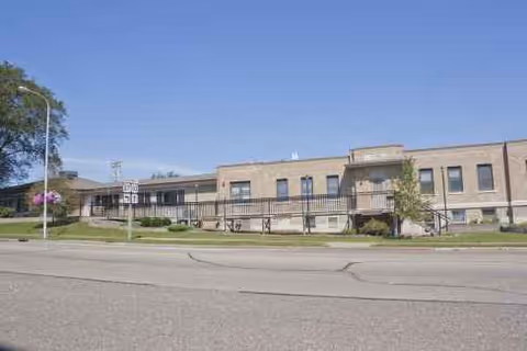 Exterior view of Homeplace of Mondovi, a beige brick senior living building along a street.