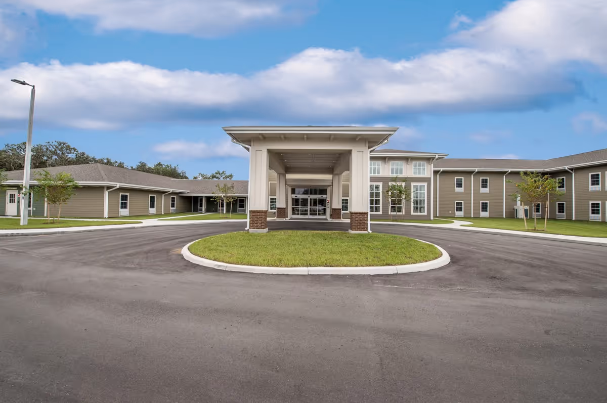 Front entrance of an assisted living building with a covered drop-off portico and circular driveway